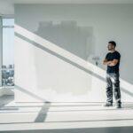 Wide shot of a professional painter standing in a sun-drenched